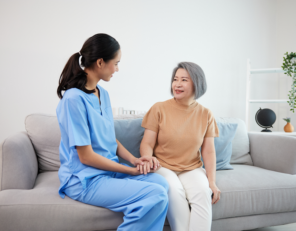 Woman in scrubs with patient on sofa